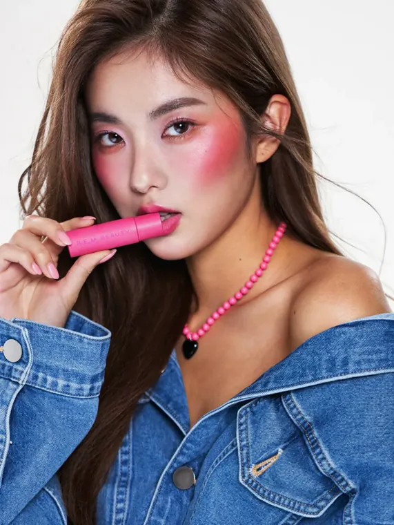 Beauty model shoot: pink blush, a pink lip stick held to the lips and a denim jacket